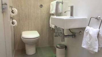 A small, modern bathroom with a toilet, sink, and trash can.