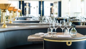A restaurant interior with a bar area, seating, and a view of the kitchen. - Thurlestone Hotel (Kingsbridge)