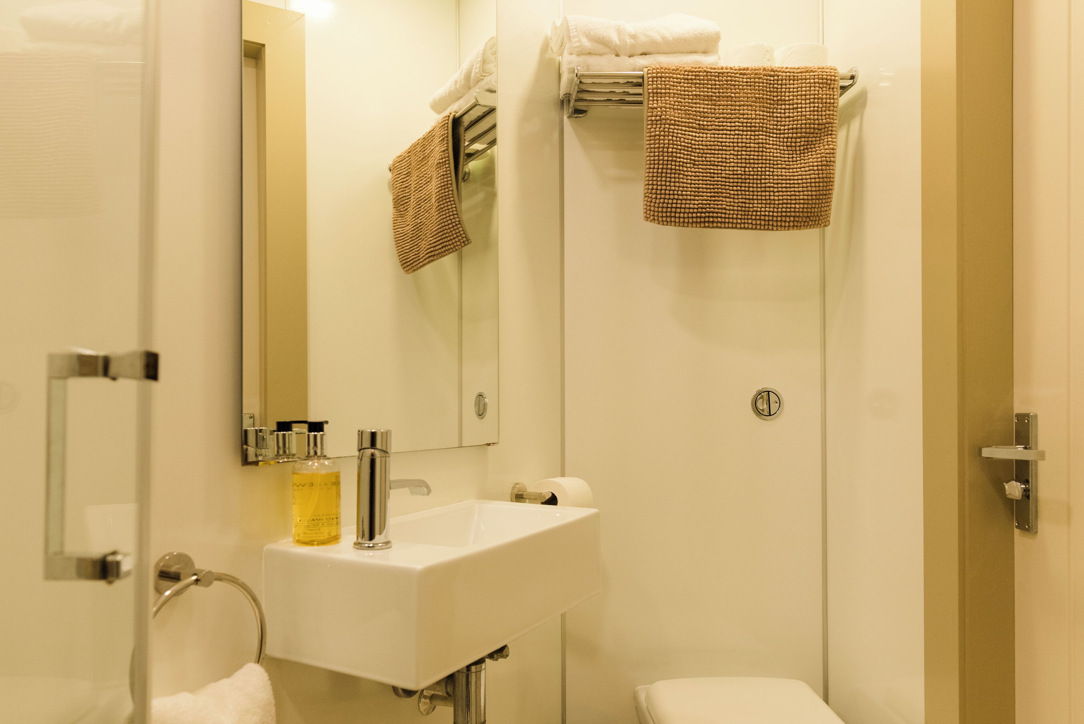 Ein Badezimmer mit Waschbecken, Spiegel, Handtuchhalter und Toilette.