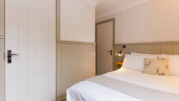 Un dormitorio con cama, una puerta y una mesita de noche con lámpara.