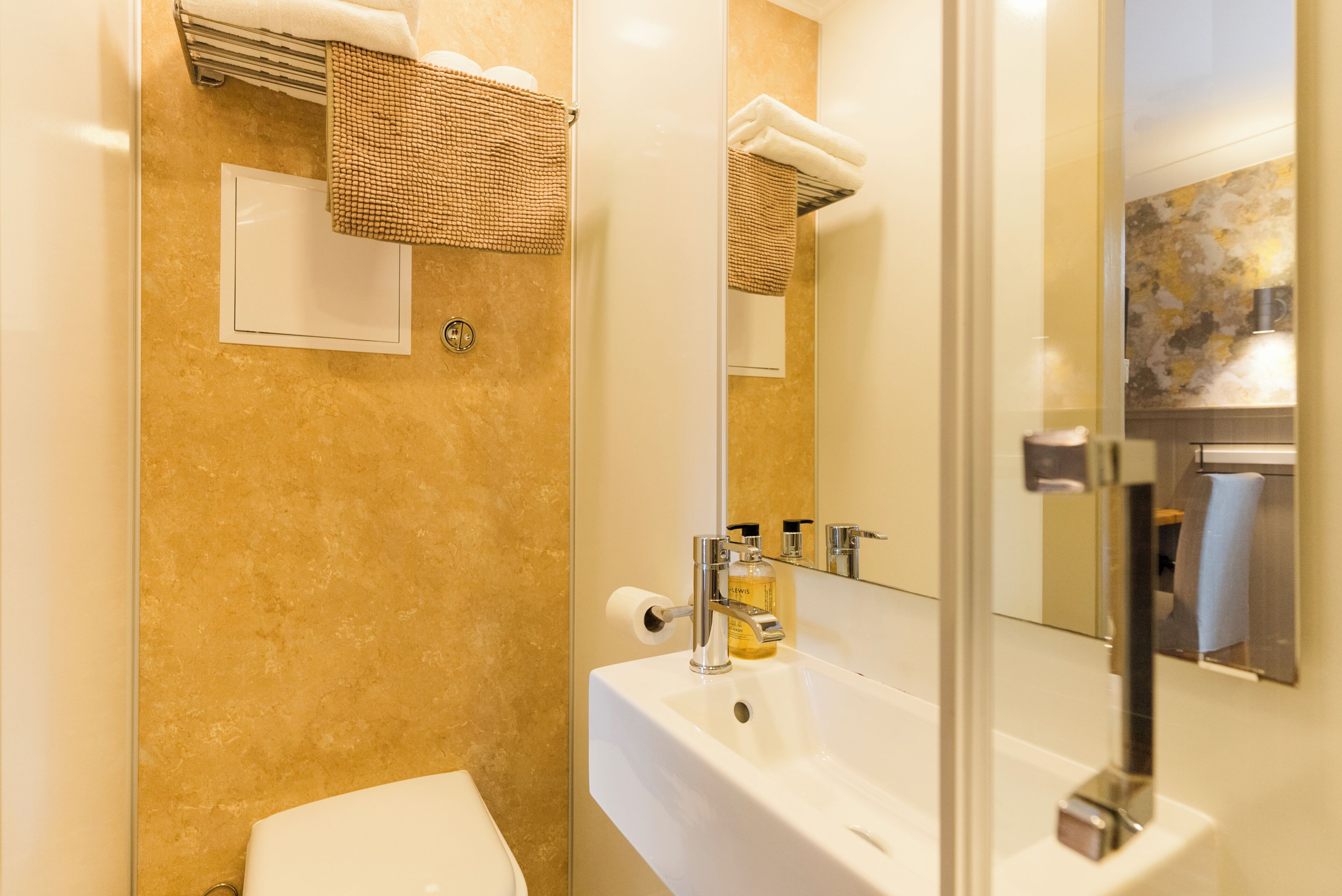 A bathroom with a white sink, a mirror, a towel rack, and a toilet.