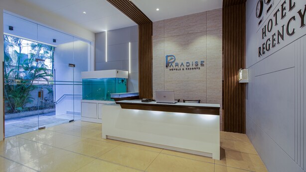 A reception desk with a laptop, a clock, and a sign for Paradise Hotels & Resorts. - Treebo Regency - Bund Garden, Dhole Patil Road (Pune)
