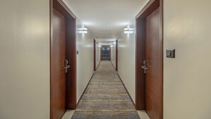 A hotel hallway with wooden doors, carpeted floor, and overhead lighting. - Treebo Regency - Bund Garden, Dhole Patil Road (Pune)
