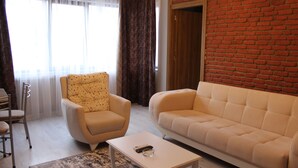 A living room with a sofa, armchair, and a coffee table. - Gurleyen Apart Otel (Izmir)
