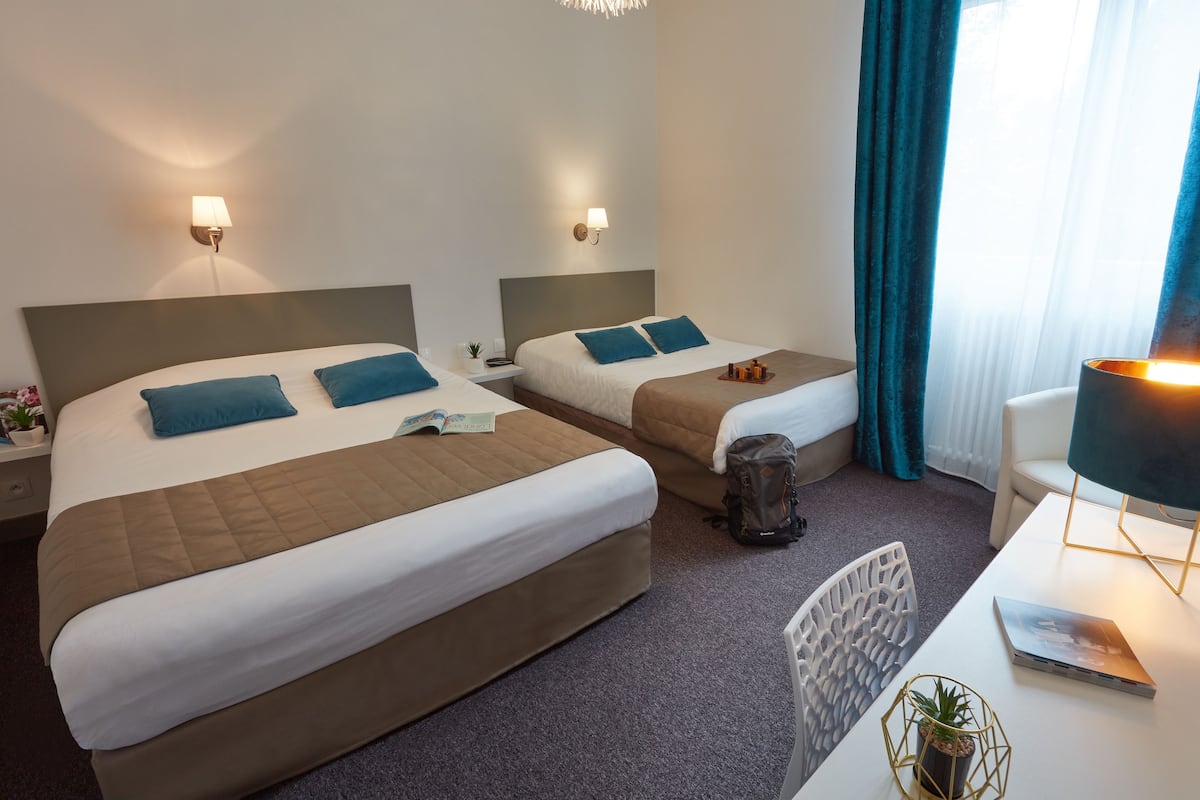 Une chambre d’hôtel avec deux lits, un bureau et une chaise.