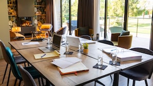 Une salle de conférence moderne, dotée d’une table en bois, d’ordinateurs portables, de cahiers et d’une cheminée.