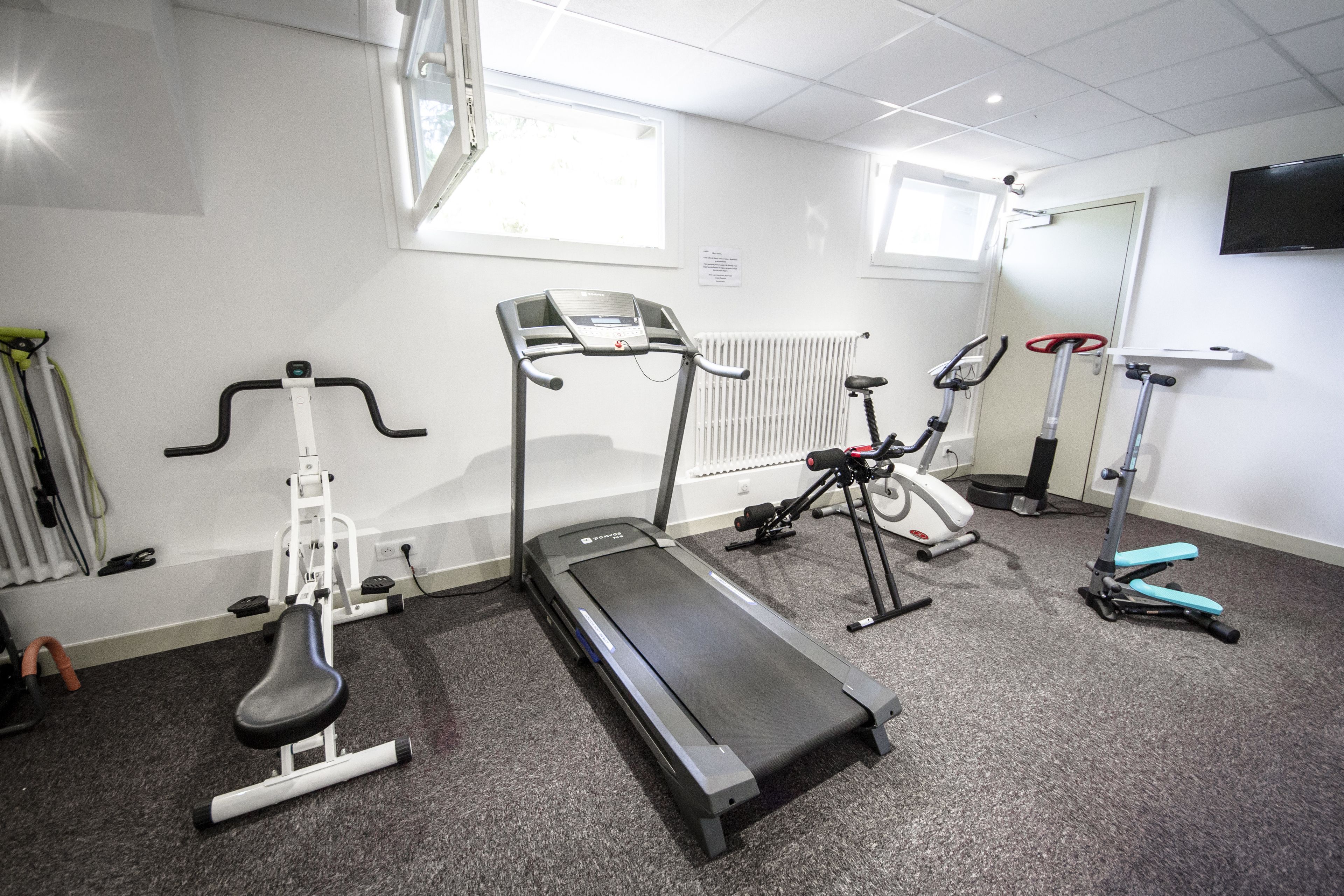 A gym with treadmills, elliptical machines, and a stationary bike.
