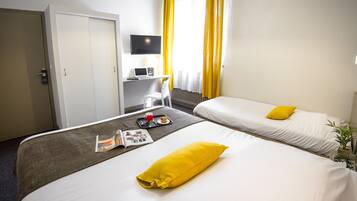 Quarto de hotel com duas camas, uma escrivaninha com computador, televisão e janela com cortinas amarelas.