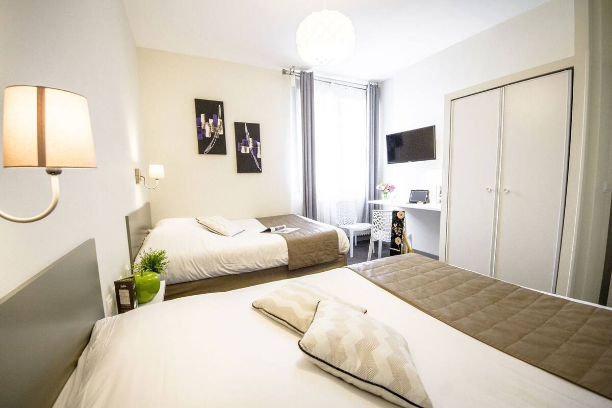 Une chambre d’hôtel avec deux lits, un bureau, une télévision et une armoire.