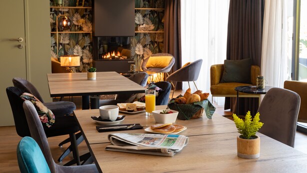 Un coin repas avec une table en bois, des chaises, des aliments pour le petit-déjeuner et une cheminée.