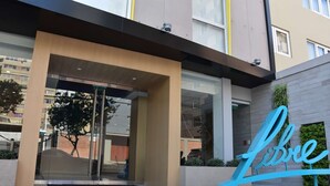 A modern building entrance with a glass door, a large 'Libre' sign, and a small garden area. - Libre Hotel, BW Signature Collection (Lima)
