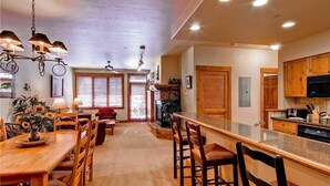 Un'ampia cucina con mobili in legno, una zona pranzo con tavolo e sedie in legno, e un angolo bar con piano in granito.