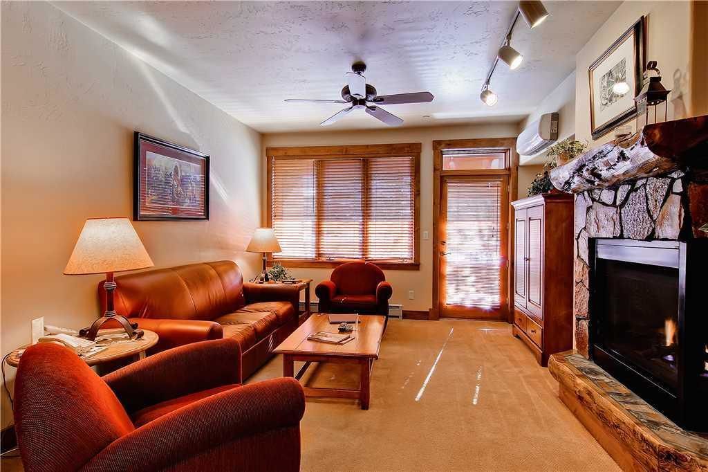 A living room with a fireplace, leather sofa, and a ceiling fan.