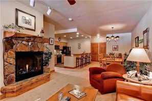 A spacious living room with a stone fireplace, a dining area, and a kitchen in the background. - 2204 Timberline Lodge, Trappeur's Crossing Apartment 2 (Steamboat Springs)