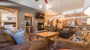 A spacious living room with a fireplace, comfortable seating, and a kitchen area in the background. - 4103 Aspen Lodge, Trappeur's Crossing (Condo) Apartment 3 (Steamboat Springs)