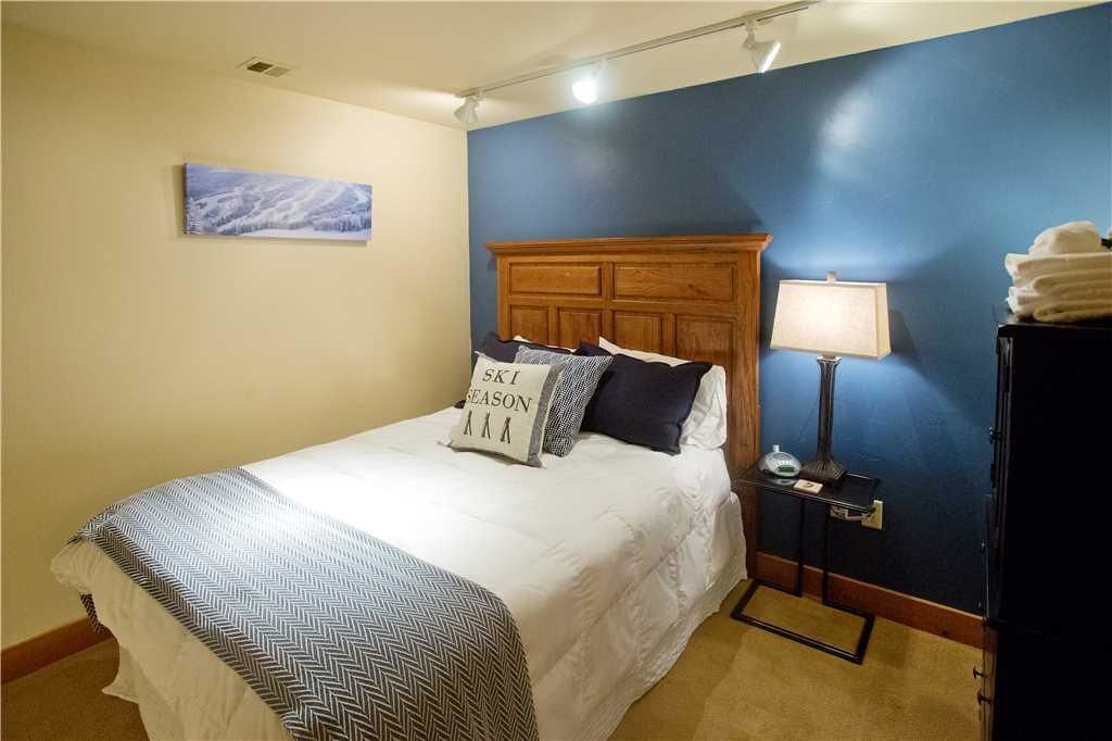 Habitación de hotel con cama, mesita de noche con lámpara, un cuadro en la pared y una pared decorada en azul.