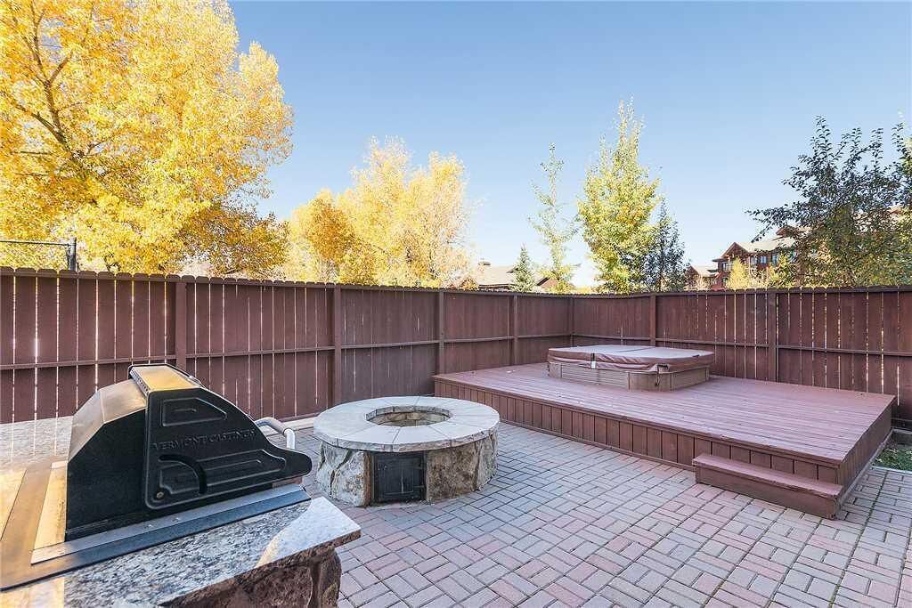 Un jardin avec un barbecue, un foyer extérieur et une terrasse en bois.