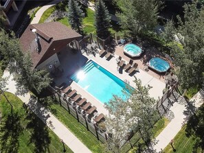 An aerial view of a residential property with a swimming pool, hot tub, and outdoor seating area surrounded by trees. - 4110 Aspen Lodge, Trappeur's Crossing Apartment 2 (Steamboat Springs)