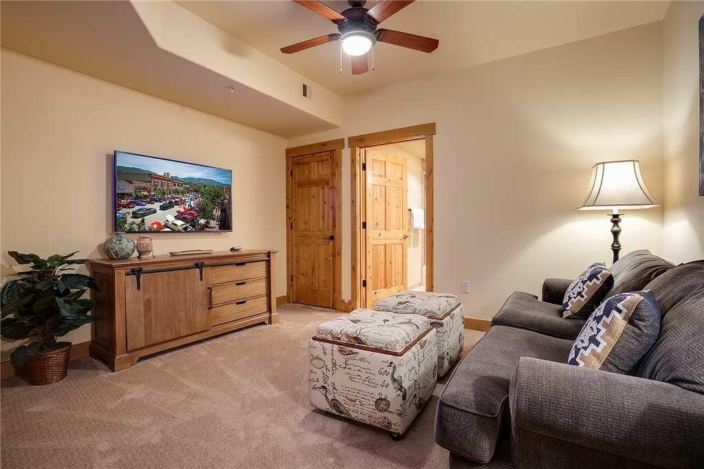 A living room with a sofa, ottoman, wooden cabinet, and a ceiling fan.