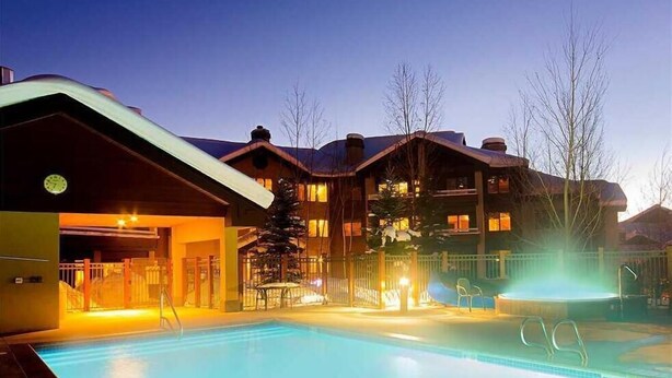 Ett hotell med en swimmingpool, en överbyggd entré och en skidlift som syns i bakgrunden.