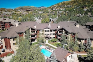 A resort with multiple buildings, a central pool, and surrounding greenery.