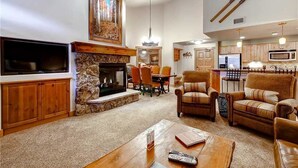 A living room with a fireplace, a dining area, and a kitchen. - 4303 Aspen Lodge, Trappeur's Crossing Apartment 3 (Steamboat Springs)