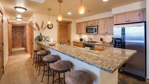 Une cuisine moderne dotée de plans de travail en granit, d’appareils électroménagers en acier inoxydable et d’armoires en bois.