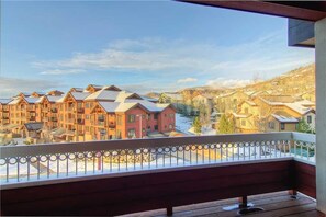 A wooden balcony with a metal railing overlooking a residential area with multiple buildings and a clear sky. - 4304 Aspen Lodge, Trappeur's Crossing Apartment 3 (Steamboat Springs)