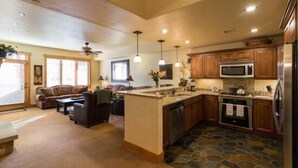 A spacious kitchen with wooden cabinets, a central island, and a stone-patterned floor. - 6106 Bear Lodge, Trappeur's Crossing Apartment 5 (Steamboat Springs)
