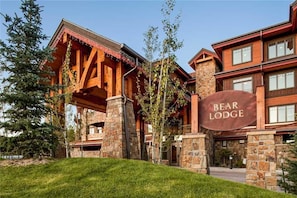 A lodge with a stone facade, wooden beams, and a sign reading "BEAR LODGE".