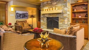 A cozy living room with a stone fireplace, comfortable seating, and a decorative centerpiece. - 6106 Bear Lodge, Trappeur's Crossing Apartment 5 (Steamboat Springs)