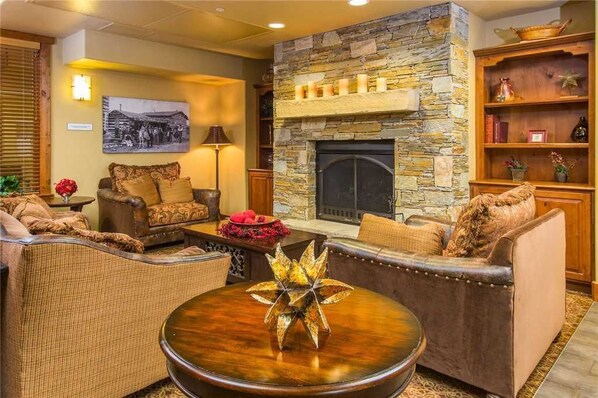 A cozy living room with a stone fireplace, comfortable seating, and a decorative centerpiece.
