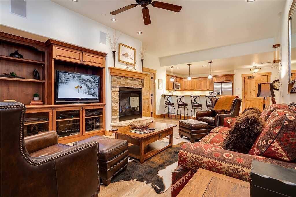 A spacious living room with a fireplace, leather furniture, and a television.