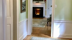 A hallway with a fireplace, a rug, and a framed picture on the wall. - Charred Oaks Inn (Versailles)