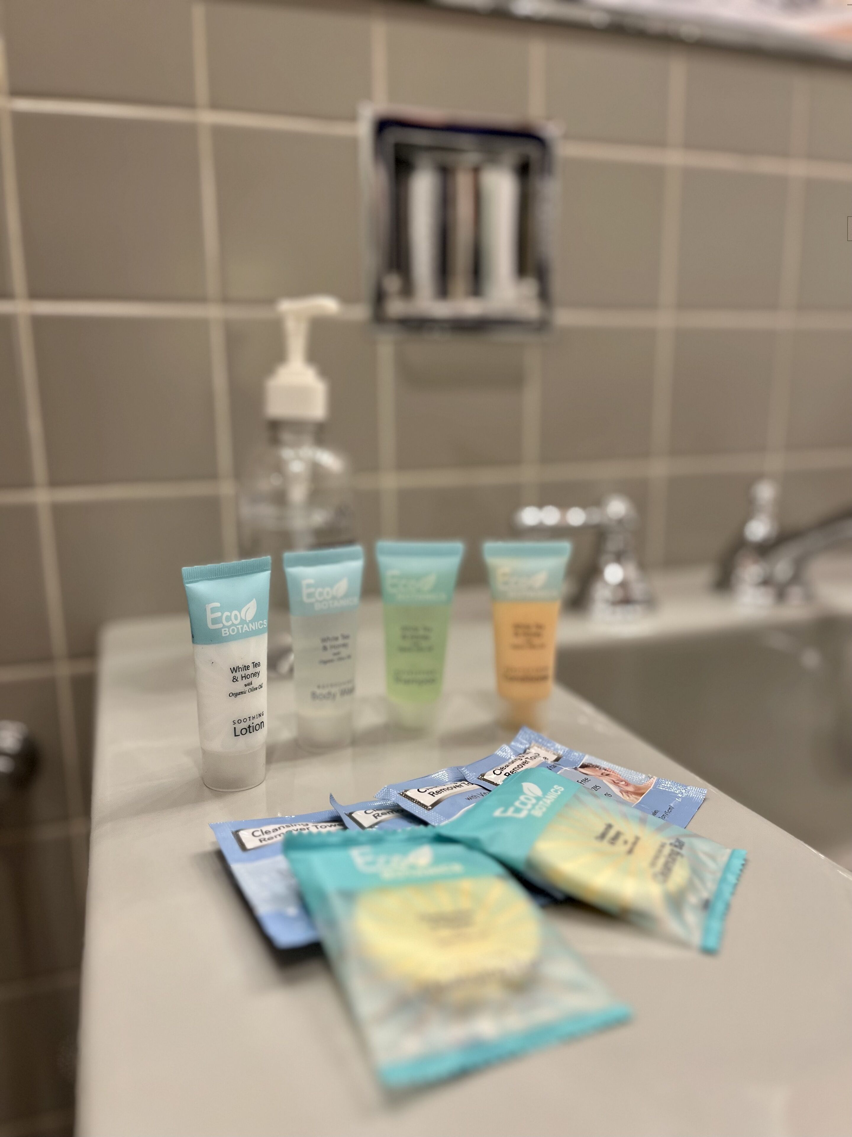 Ein Badezimmer-Waschtisch mit verschiedenen Pflegeprodukten, darunter eine Lotionflasche, Duschgeltuben und Seifenstückchen.