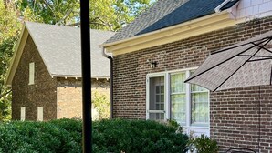 A patio with a table and chairs, a fire pit, and a brick building in the background. - Charred Oaks Inn (Versailles)