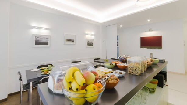 Un espace repas moderne avec un buffet proposant des fruits, du pain et diverses autres collations.