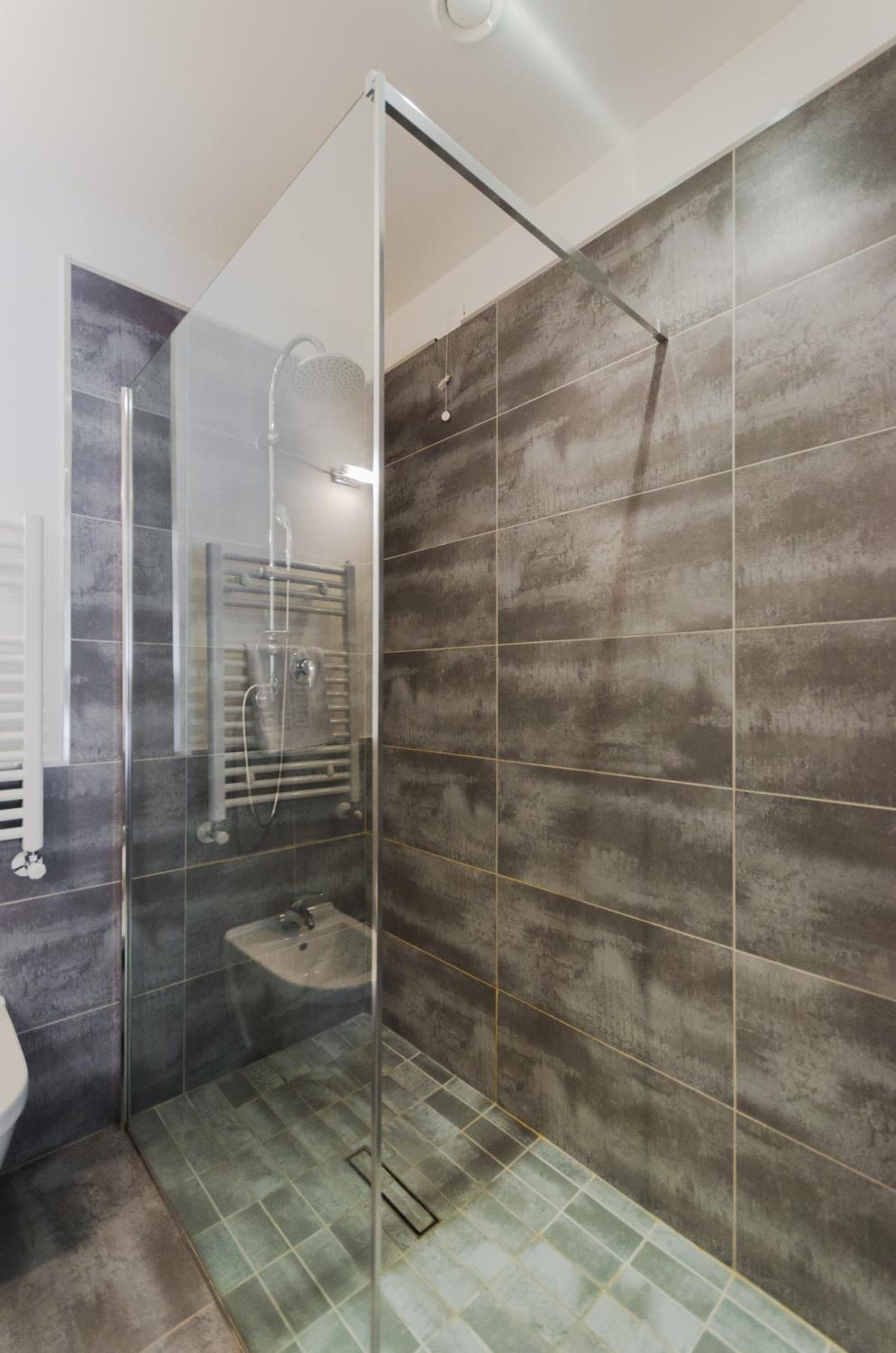 Een moderne badkamer met een douchecabine van glas, een ingebouwd wastafelmeubel en een handdoekrek.