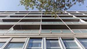 Un immeuble à plusieurs étages doté d’une architecture moderne, caractérisé par une façade composée d’une grille de fenêtres et de balcons.