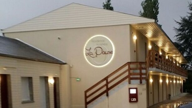 Un bâtiment sur lequel on peut lire l’inscription « La Pause », et un escalier menant à une zone abritée.