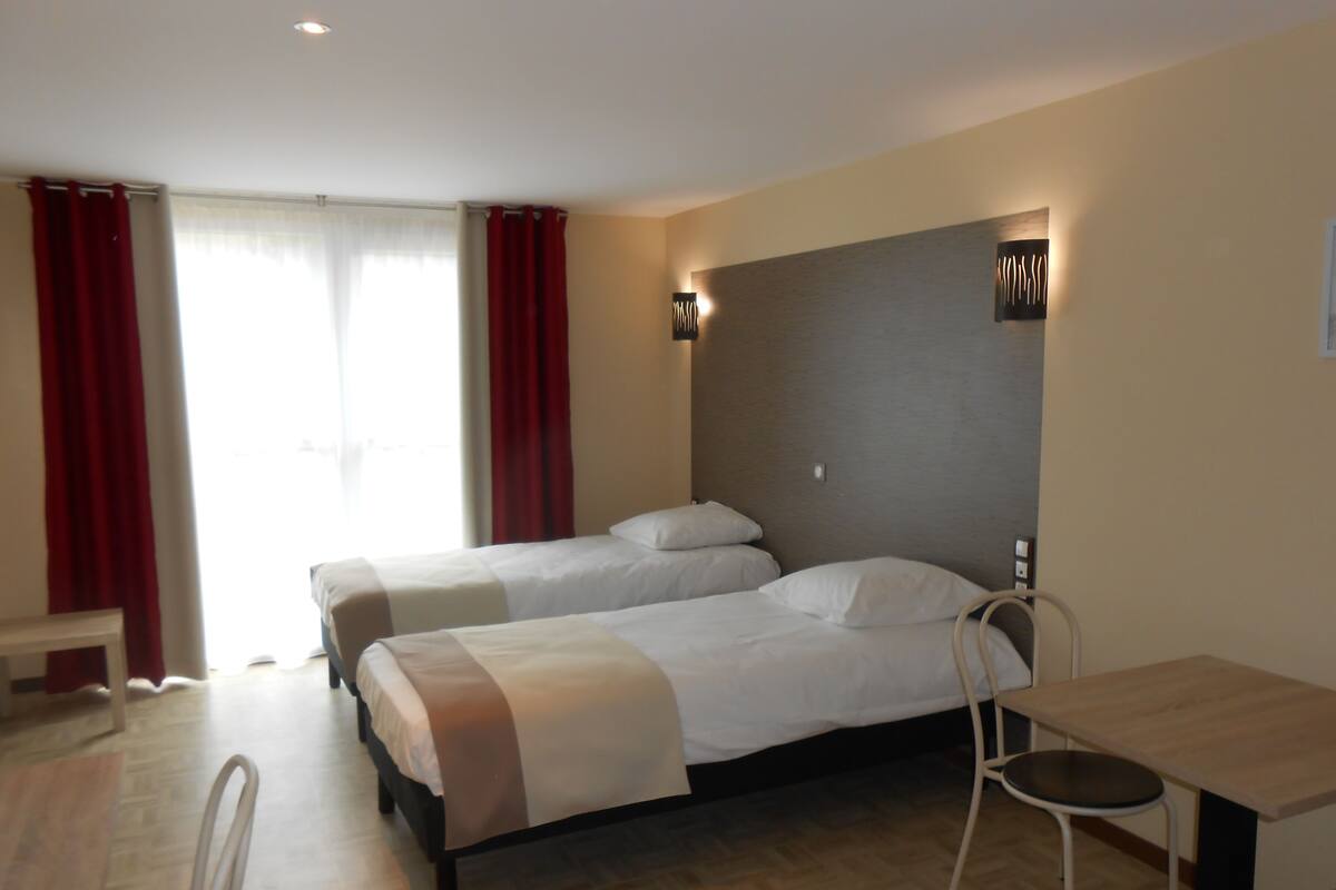Ein Hotelzimmer mit zwei Betten, einem Schreibtisch und einem Stuhl.