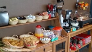 Un buffet est installé sur une table en bois, avec différents plats et ustensiles à disposition.