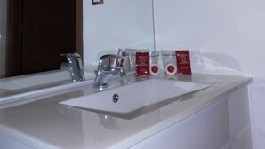 Une salle de bain avec un lavabo blanc, un miroir et un sèche-mains fixé au mur.