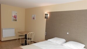 Une chambre d’hôtel avec un lit, un bureau et une chaise.