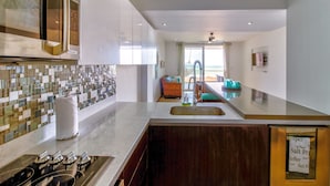 Een moderne keuken met een groot schiereiland, een inbouwoven en uitzicht op een balkon.