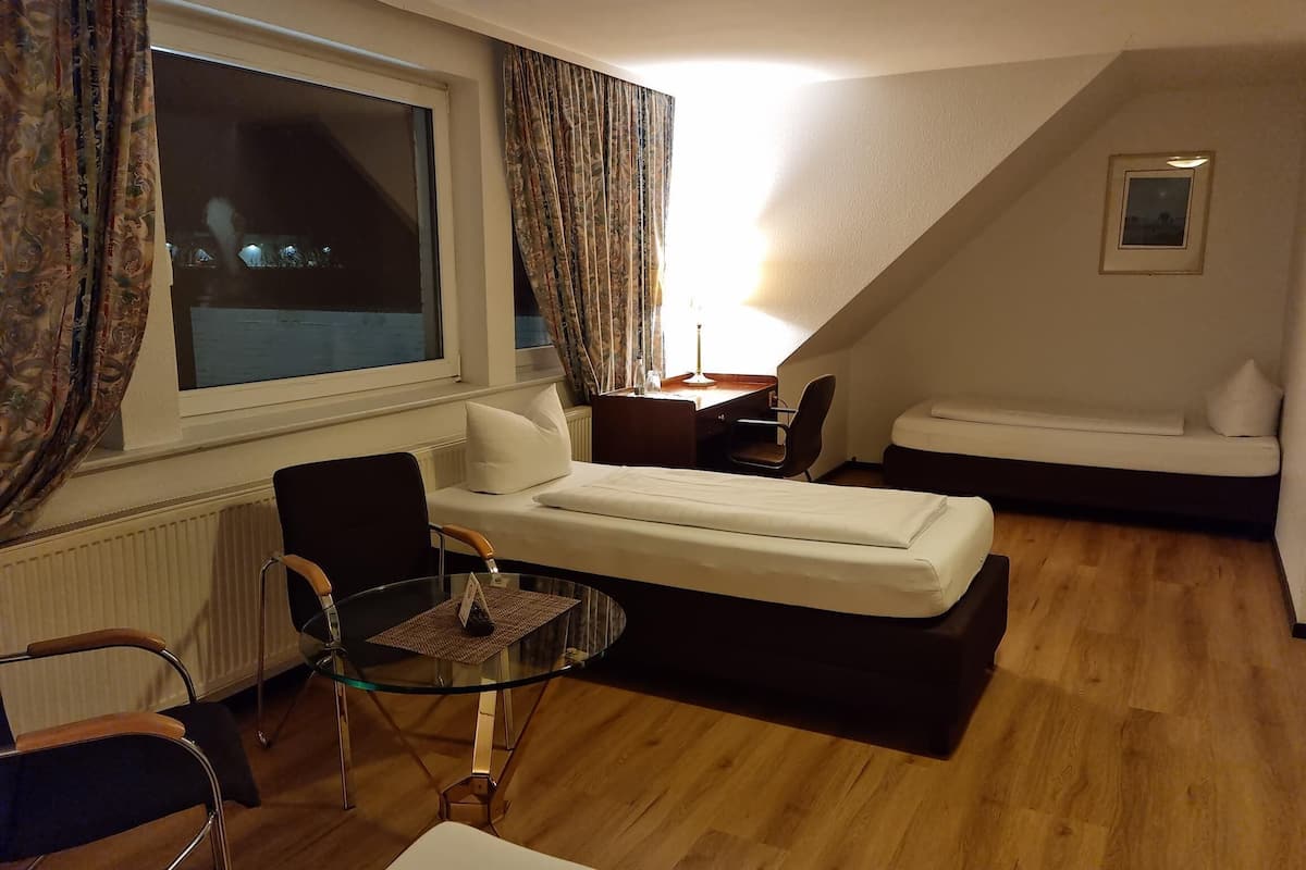 A small, cozy hotel room with a bed, a desk, a chair, and a glass table.