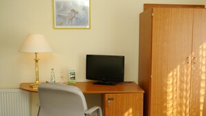 A room with a desk, a computer, a chair, a lamp, a radiator, and a wardrobe. - Erbenholz Hotel (Laatzen)