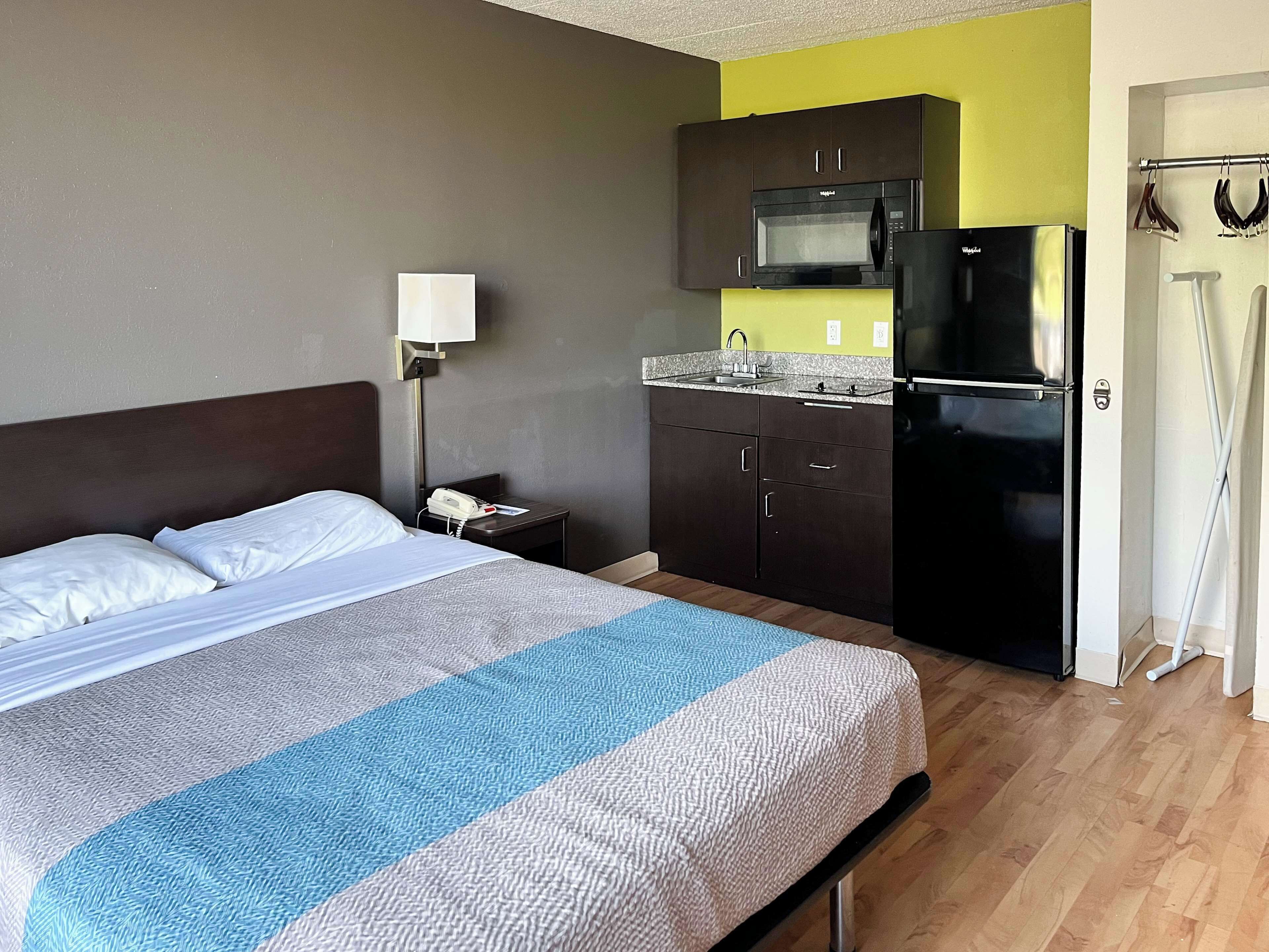 Une chambre d’hôtel équipée d’un lit, d’une table de chevet, d’un four à micro-ondes, d’un réfrigérateur et d’une petite kitchenette.