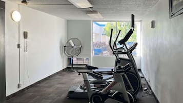 Ett gym med motionscyklar, ett löpband och en fläkt.