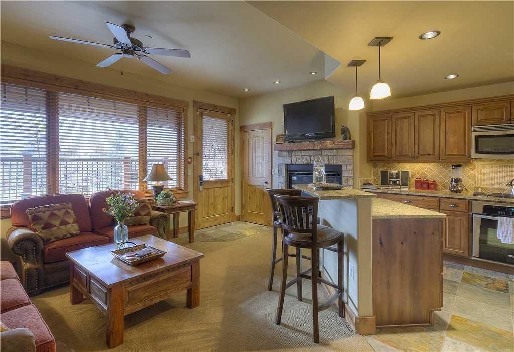 A spacious living room with a fireplace, a dining area, and a kitchen with wooden cabinets and a large island.